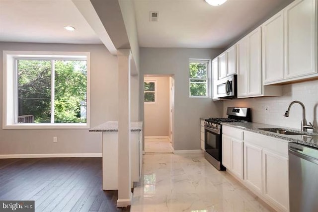 kitchen with stainless steel appliances, a sink, light stone counters, baseboards, and recessed lighting