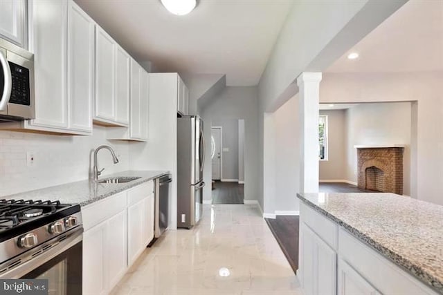 kitchen with stainless steel appliances, a sink, white cabinets, light stone counters, and recessed lighting