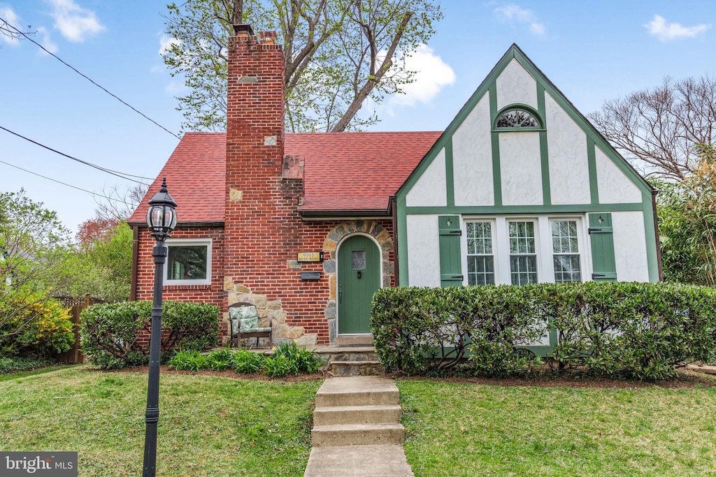 9505 Riley Rd, Silver Spring, MD 20910 - english style home with stucco siding, stone siding, a front lawn, a shingled roof, and a chimney