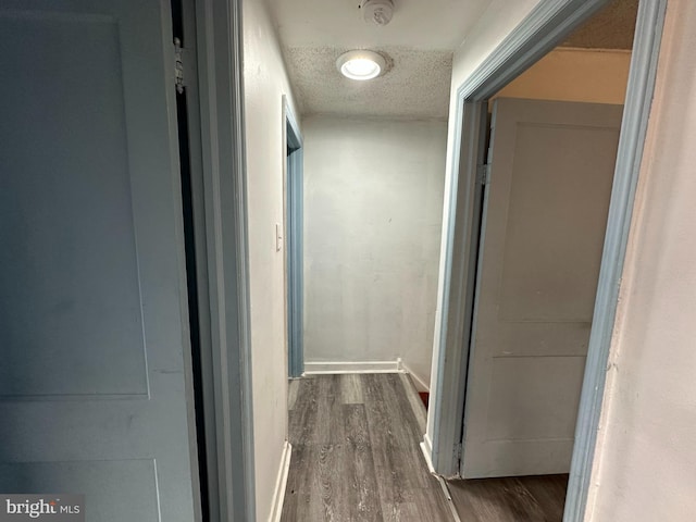 hallway with dark wood-type flooring and a textured ceiling