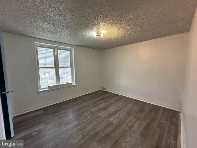 spare room featuring baseboards, dark wood-type flooring, and a textured ceiling