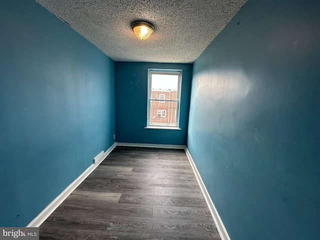 unfurnished room with baseboards, a textured ceiling, and wood finished floors