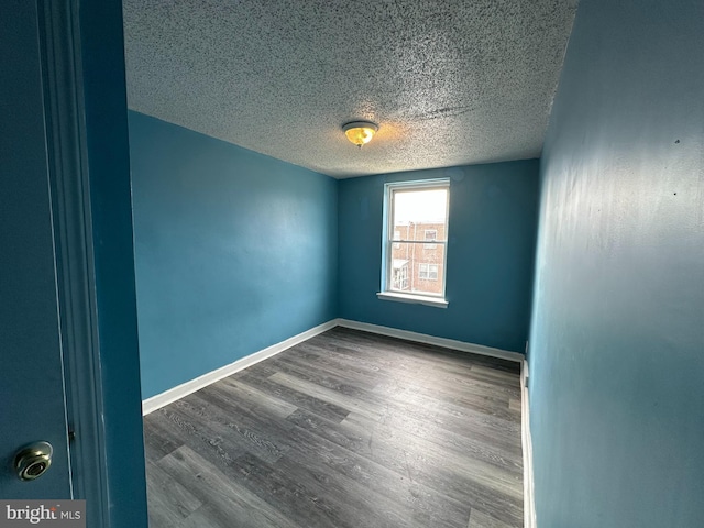 empty room with baseboards, wood finished floors, and a textured ceiling