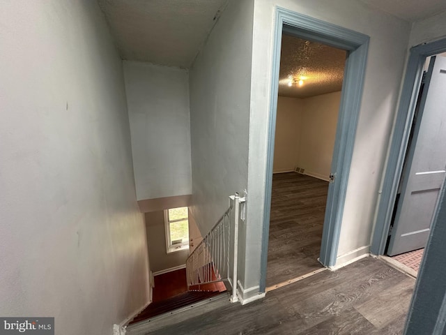 stairway with visible vents, a textured ceiling, baseboards, and wood finished floors