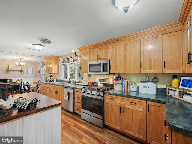 2796 Green Spring Rd, Winchester, VA 22603 - kitchen featuring wood finished floors, a chandelier, appliances with stainless steel finishes, dark countertops, and a sink
