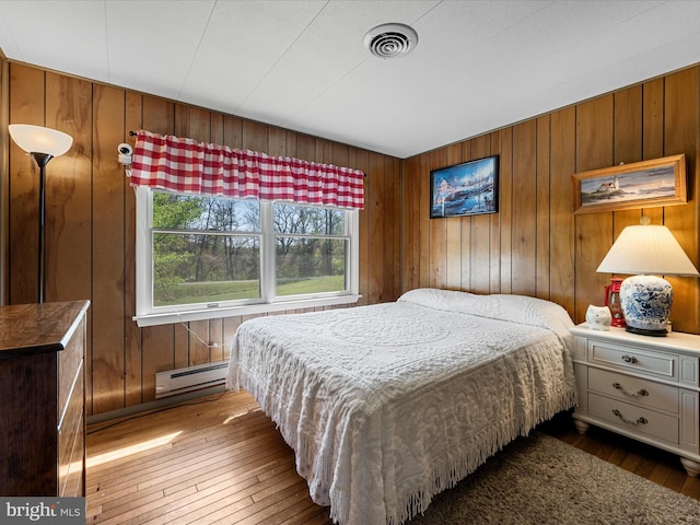 2796 Green Spring Rd, Winchester, VA 22603 - bedroom featuring baseboard heating, visible vents, hardwood / wood-style flooring, and wood walls