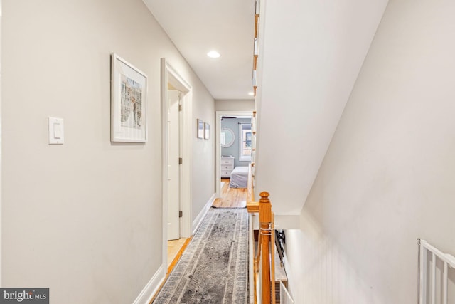 corridor with baseboards, light wood-type flooring, and recessed lighting