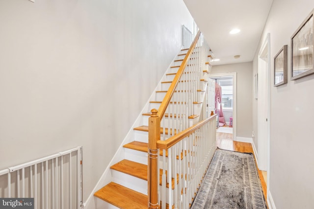 staircase with baseboards, wood finished floors, and recessed lighting