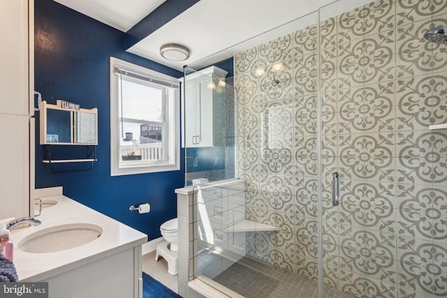 bathroom featuring a stall shower, toilet, a sink, baseboards, and double vanity