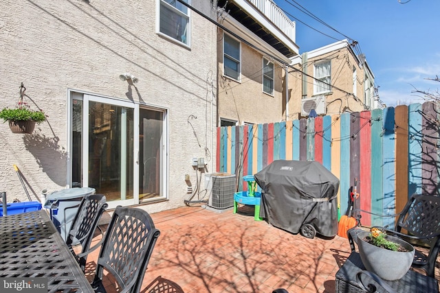 view of patio featuring central AC unit, fence, and a grill