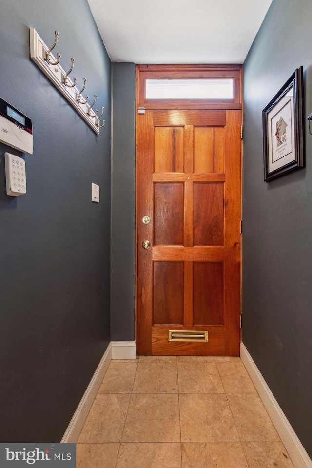 doorway to outside featuring baseboards and tile patterned flooring
