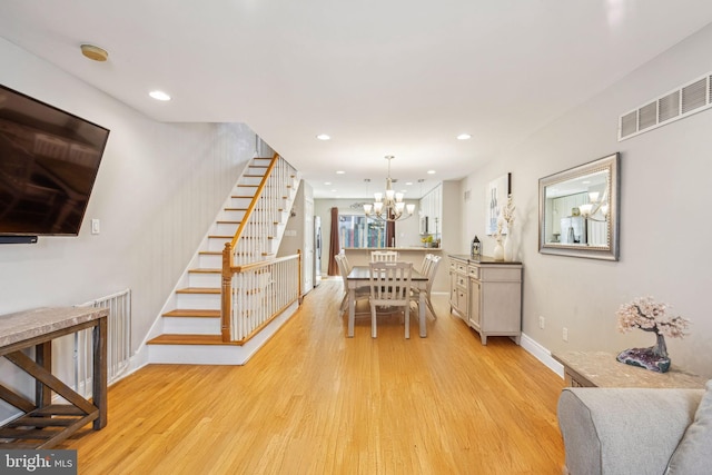 dining area featuring light wood-style flooring, visible vents, baseboards, stairway, and a notable chandelier