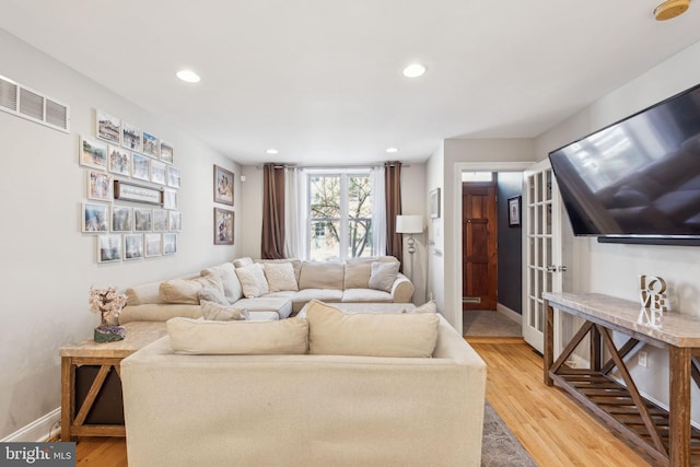 living area featuring baseboards, visible vents, light wood-style floors, and recessed lighting