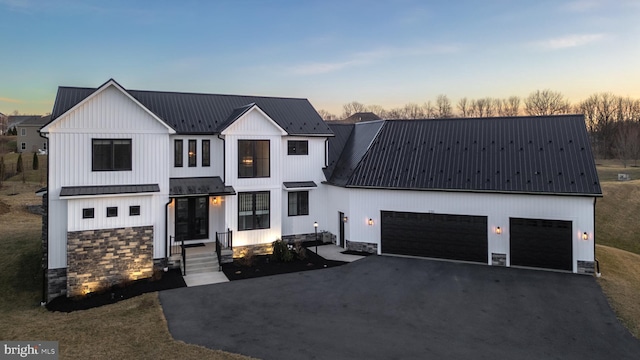 330 Trout Rd, State College, PA 16801 - modern farmhouse style home with stone siding, board and batten siding, aphalt driveway, metal roof, and a garage