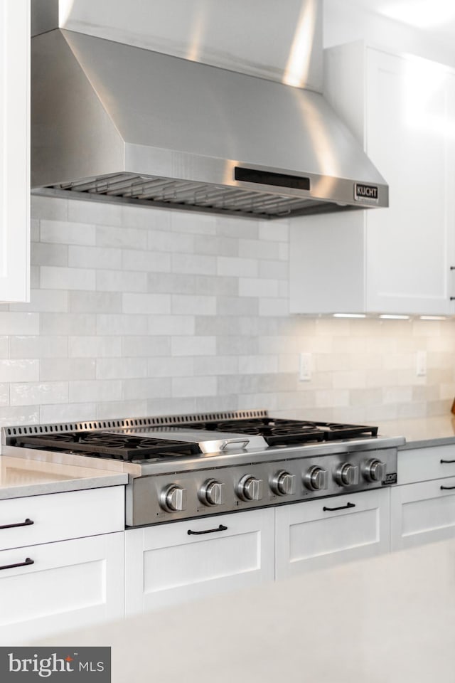 330 Trout Rd, State College, PA 16801 - interior details featuring light countertops, stainless steel gas stovetop, wall chimney range hood, white cabinets, and decorative backsplash