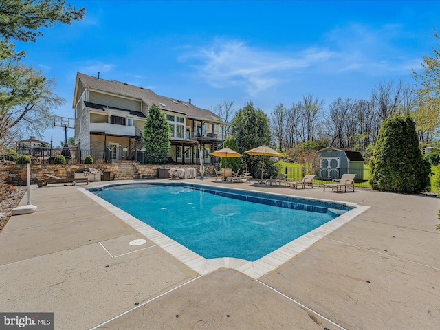 view of swimming pool featuring a storage shed, a fenced in pool, an outbuilding, fence, and a patio