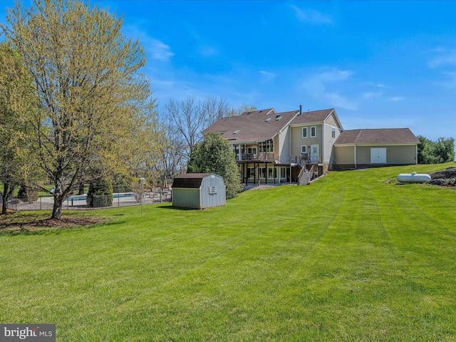 back of property featuring a storage unit, stairway, a deck, an outdoor structure, and a yard
