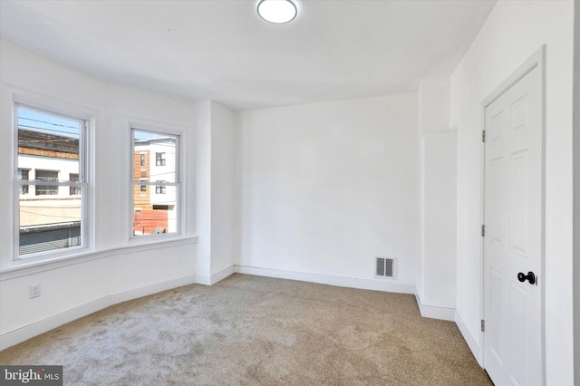 empty room featuring baseboards, visible vents, and carpet flooring