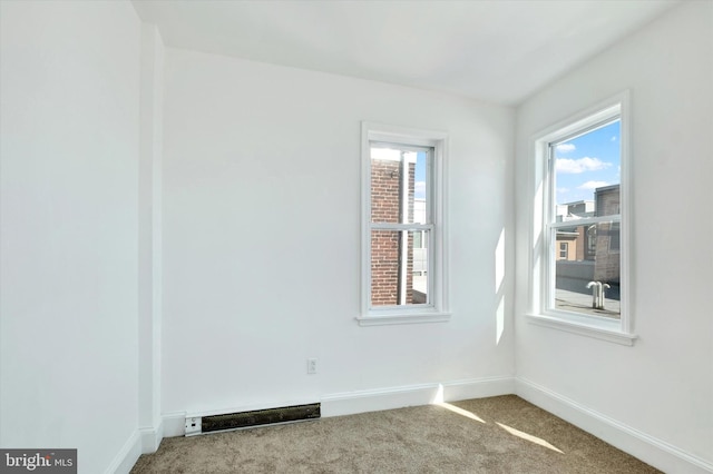 spare room featuring plenty of natural light, baseboards, visible vents, and carpet