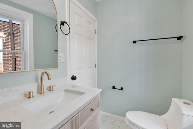 half bath featuring marble finish floor, baseboards, toilet, and vanity