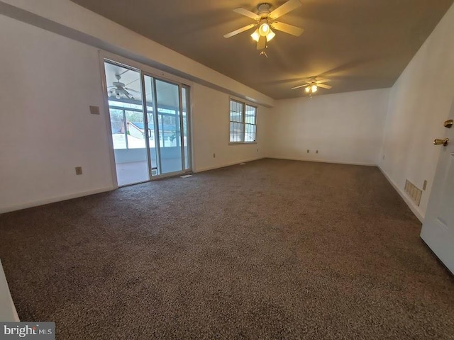 spare room featuring baseboards, ceiling fan, dark carpet, and visible vents