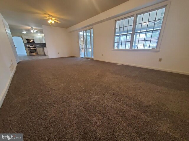 unfurnished living room featuring baseboards, a ceiling fan, and carpet