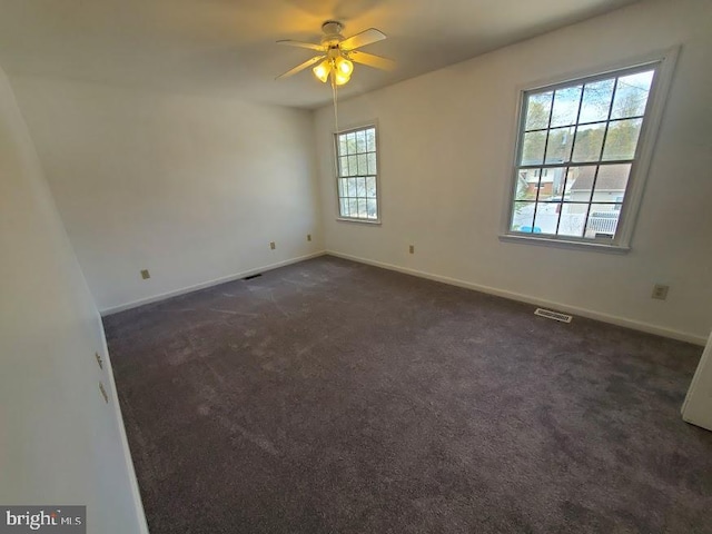 empty room with a ceiling fan, baseboards, visible vents, and dark carpet