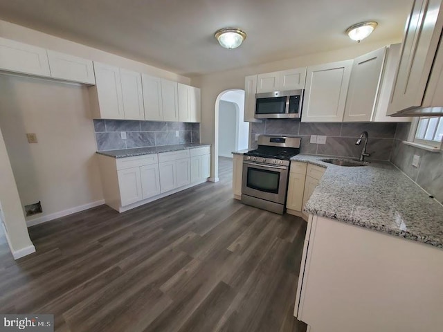kitchen featuring backsplash, white cabinets, appliances with stainless steel finishes, and a sink