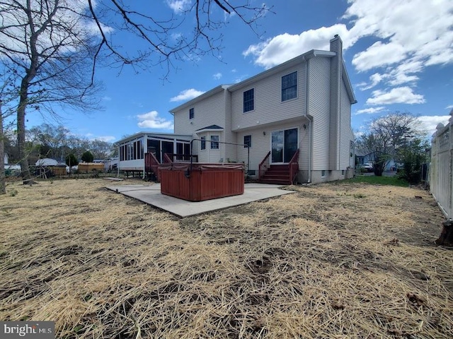 rear view of house with a chimney, a sunroom, a hot tub, fence, and a patio