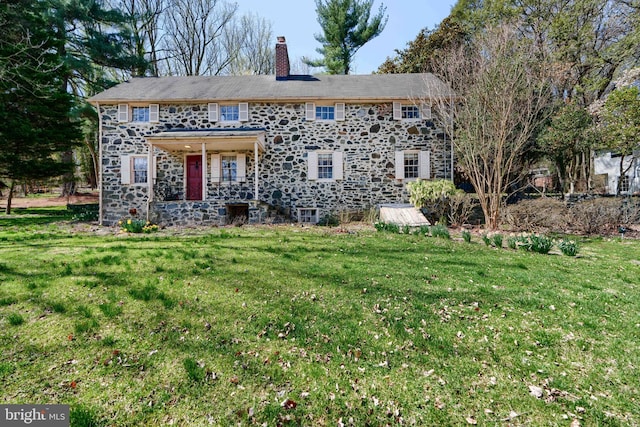 view of front of home with stone siding, a chimney, and a front lawn