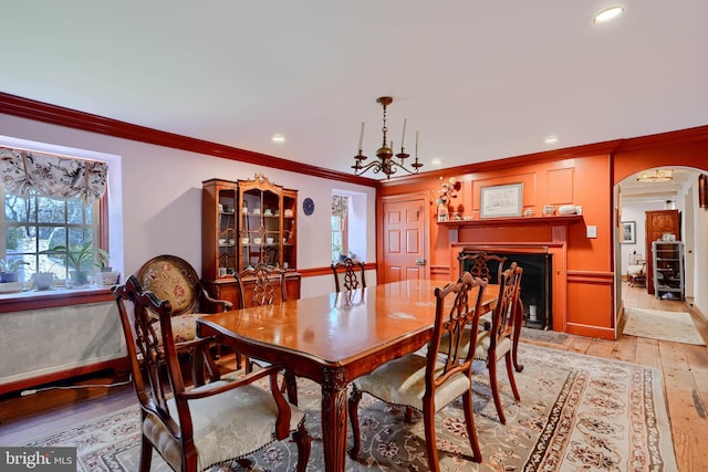 dining area featuring recessed lighting, arched walkways, light wood-style flooring, and crown molding