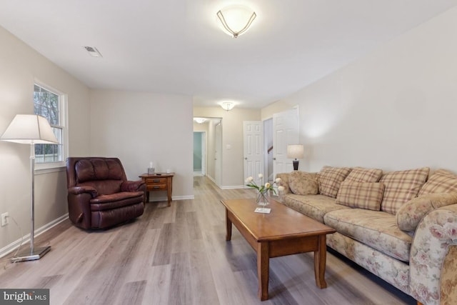 living room featuring light wood-style flooring, baseboards, and visible vents