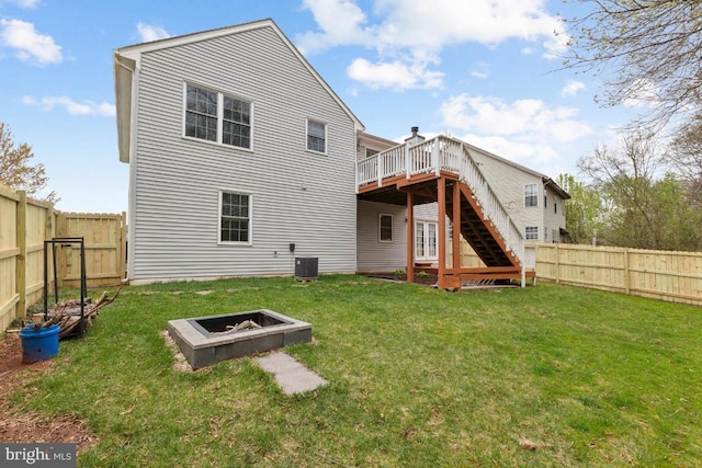 rear view of house with a fenced backyard, a fire pit, a wooden deck, and stairway