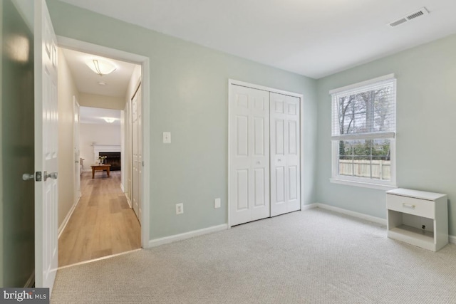 unfurnished bedroom with baseboards, visible vents, carpet flooring, and a fireplace