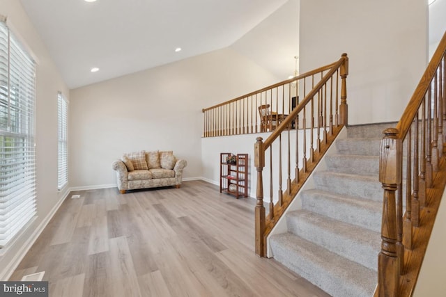 stairs featuring baseboards, high vaulted ceiling, wood finished floors, and recessed lighting