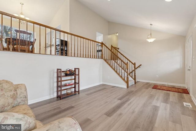 interior space featuring baseboards, visible vents, high vaulted ceiling, and wood finished floors