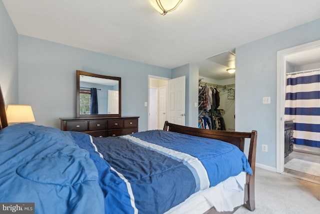 bedroom with a closet, carpet floors, a spacious closet, ensuite bath, and baseboards