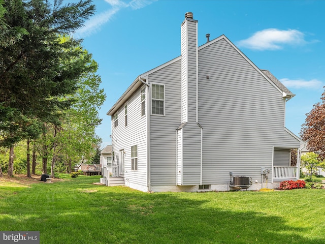 back of property featuring a lawn, central AC, and a chimney