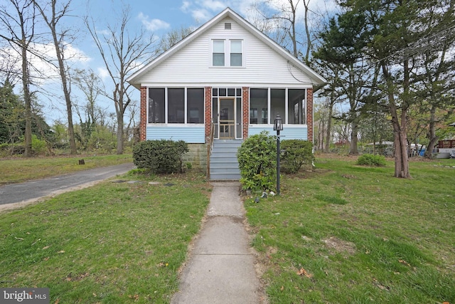 bungalow-style home with a sunroom and a front yard