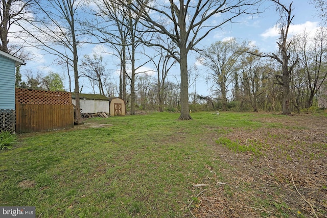 view of yard featuring a storage shed, fence, and an outdoor structure