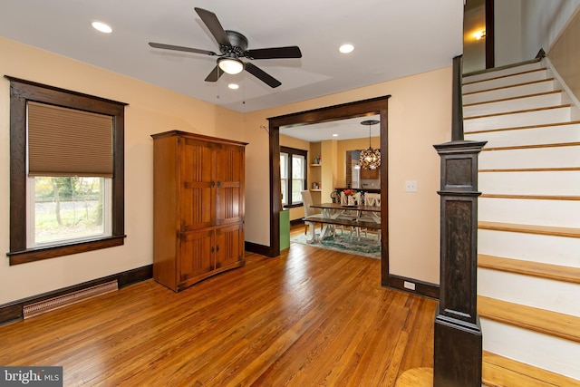 interior space featuring recessed lighting, light wood-type flooring, stairs, and ceiling fan with notable chandelier