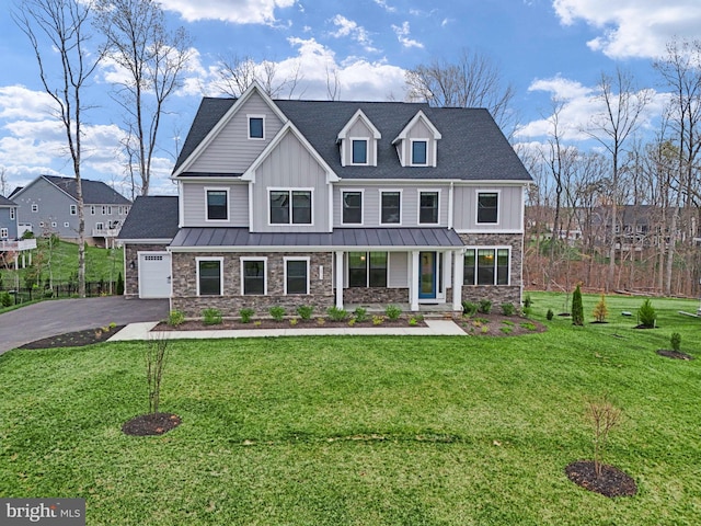 view of front of home with a front yard, driveway, stone siding, and board and batten siding