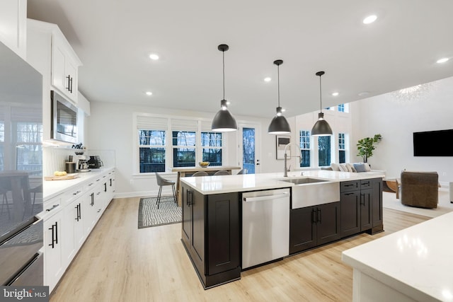kitchen with light countertops, appliances with stainless steel finishes, a sink, and white cabinetry