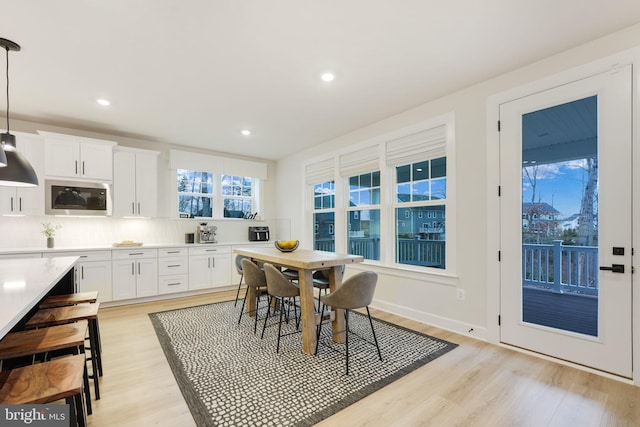 dining room featuring light wood finished floors, baseboards, and recessed lighting