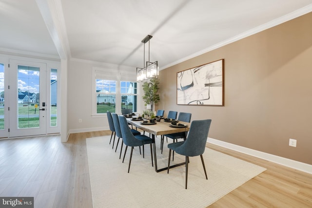 dining room with light wood-style flooring, an inviting chandelier, baseboards, and ornamental molding