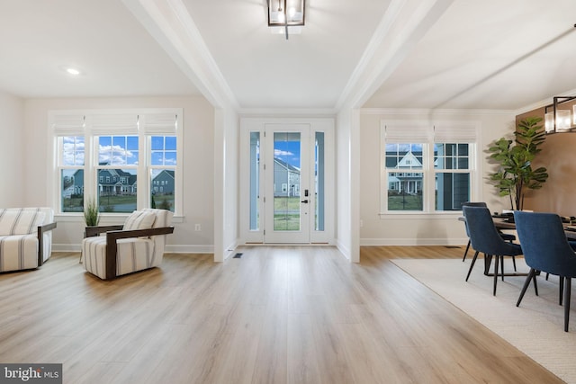 interior space featuring light wood-style floors, ornamental molding, and a healthy amount of sunlight