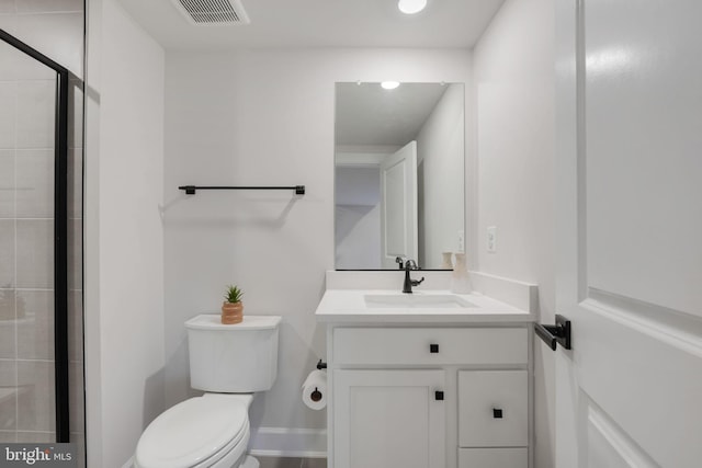 bathroom with vanity, baseboards, toilet, tiled shower, and visible vents