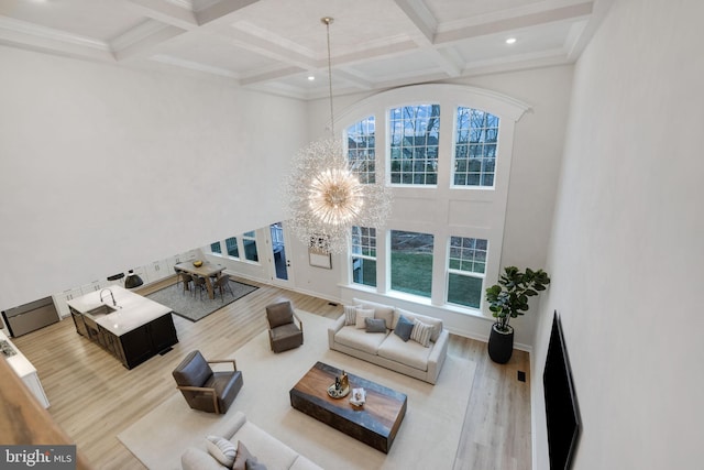 living room with a wealth of natural light, a chandelier, and wood finished floors