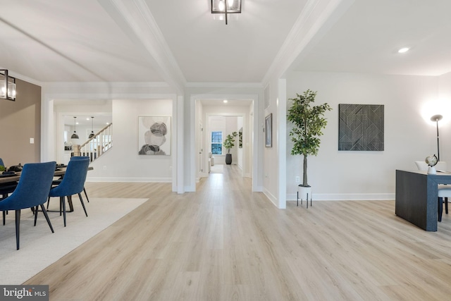 entryway with ornamental molding, baseboards, light wood-type flooring, and stairway