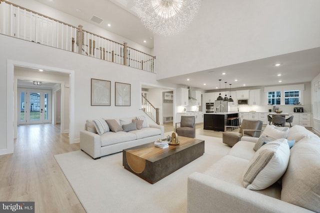 living room with light wood-style floors, visible vents, recessed lighting, stairway, and a notable chandelier